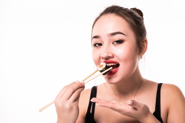 Close portrait of a woman taste eats sushi roll holding with wooden chopsticks