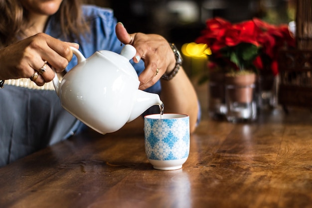 Close shot of female pouring water in a cup with a blurred background