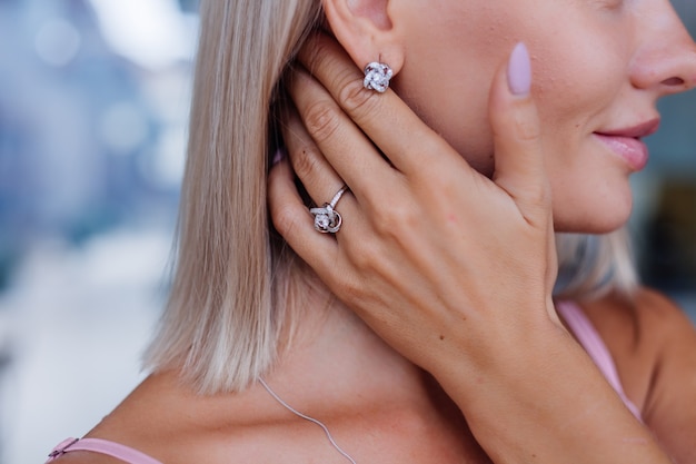 Close shot of rich luxury woman in dress hand and ear wearing earrings and ring on finger