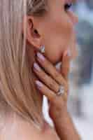 Free photo close shot of rich luxury woman in dress hand and ear wearing earrings and ring on finger