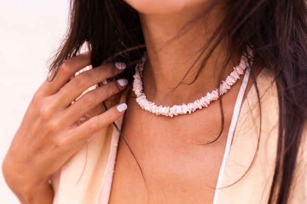 Close shot of woman wearing sea shell necklace on beach