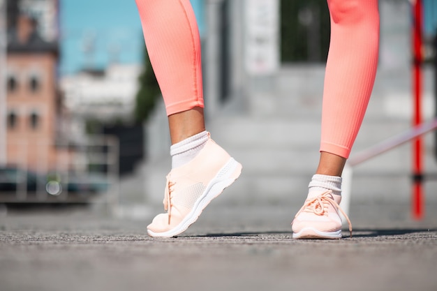 Close shot of womans legs wearing pink sport sneakers and leggings