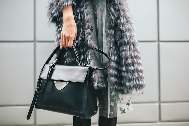 Foto gratuita chiudere i dettagli degli accessori della donna alla moda che cammina in città in caldo cappotto di pelliccia, stagione invernale, clima freddo, tenendo borsa in pelle, tendenza moda di strada