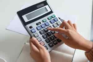 Free photo close-up of accountant using calculator while examining report