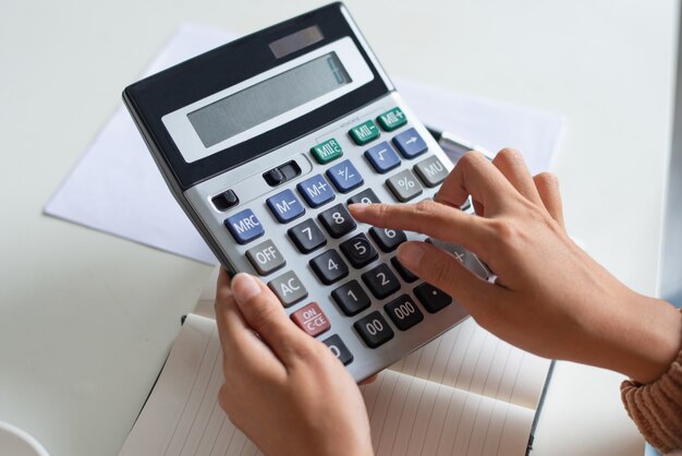 Free Photo close-up of accountant using calculator while examining report