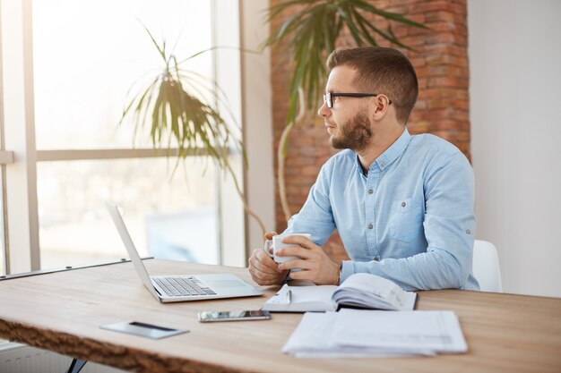 Close up of adult businessman sitting in office looking aside with thoughtful expression