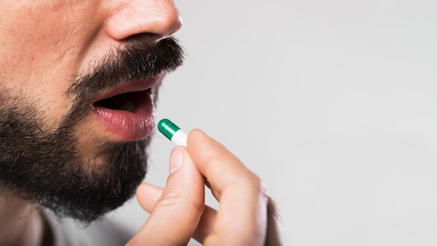 Close-up adult male swallowing a capsule