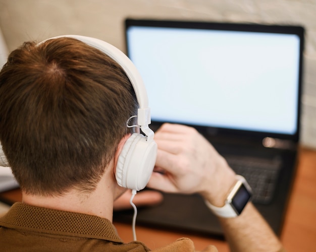 Close-up adult male working with headphones on