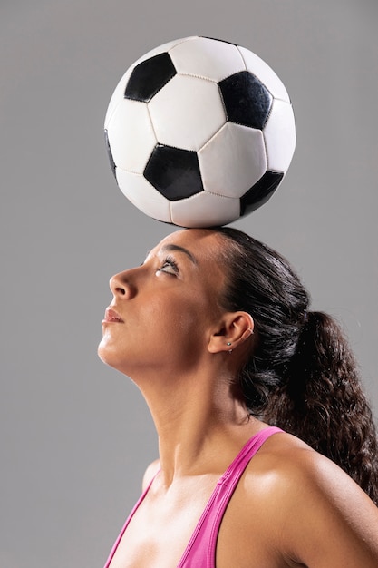 Close-up adult woman holding ball on head