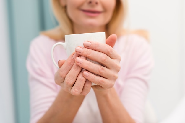 一杯のコーヒーを保持しているクローズアップの成人女性