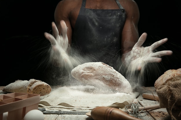 Close up of african-american man cooks fresh cereal, bread, bran on wooden table. Tasty eating, nutrition, craft product. Gluten-free food, healthy lifestyle, organic and safe manufacture. Handmade.