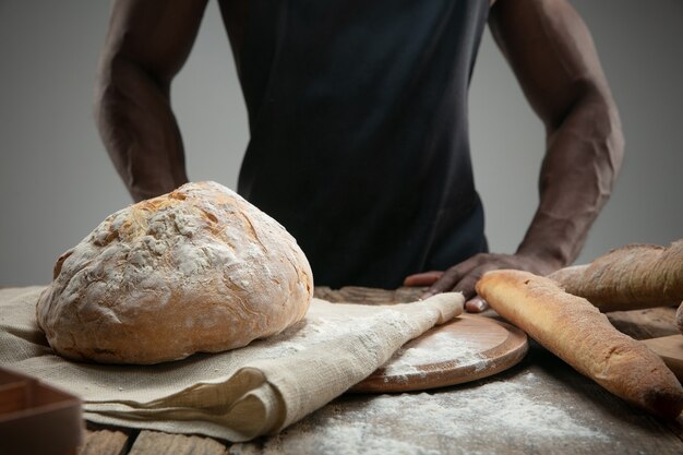 Close up of african-american man cooks fresh cereal, bread, bran on wooden table. Tasty eating, nutrition, craft product. Gluten-free food, healthy lifestyle, organic and safe manufacture. Handmade.