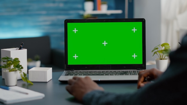 밝은 거실에서 녹색 화면 노트북을 사용하는 아프리카계 미국인 남성 클로즈업