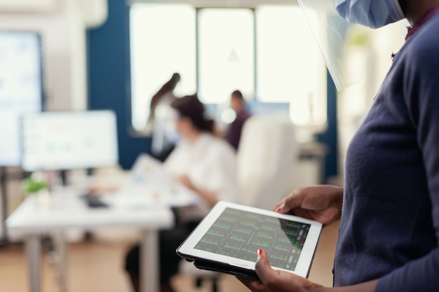 Close up of african businesswoman checking statistics graph on tablet pc