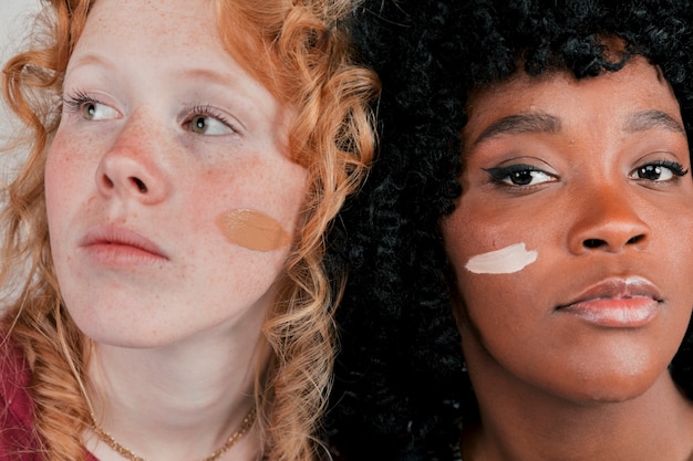 피부 톤 기초 크림을 가진 아프리카와 백인 여자의 얼굴 클로즈업