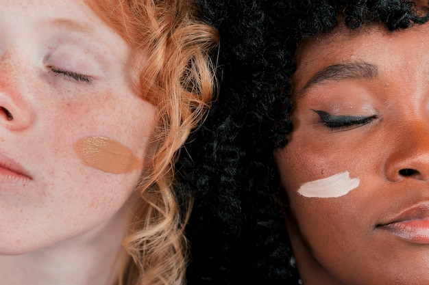 Close-up of an african and caucasian woman's face with skin tone foundation cream