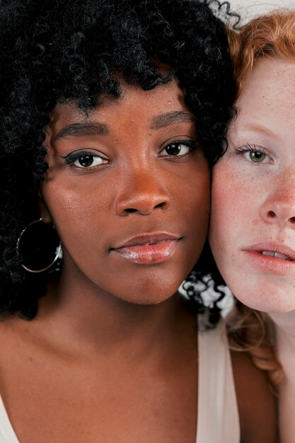 Close-up of african and caucasian women touching their cheeks looking at each other