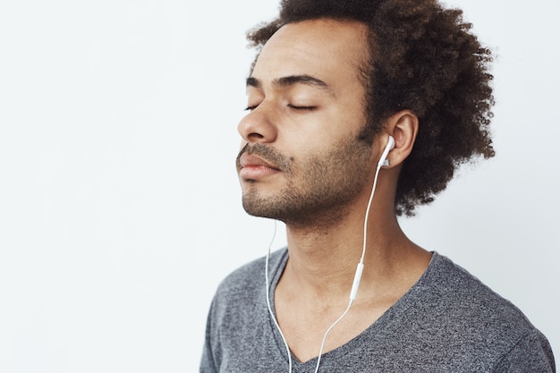 Close up of african man listening to music in headphones with closed eyes.