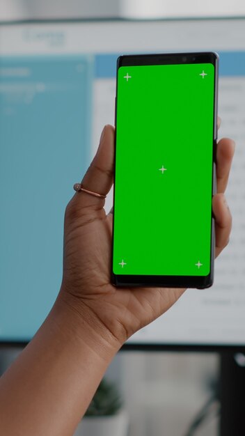Крупный план африканской женщины, держащей макет телефона с клавишами цветности зеленого экрана с изолированным дисплеем в руках, имеющих онлайн-видеоконференцию. Студент, работающий удаленно из дома, смотрит видео