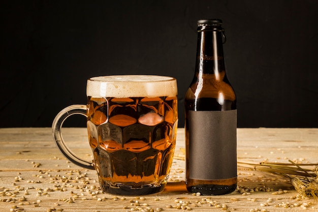 Close-up of alcoholic glass and bottle with ears of wheat on wooden surface