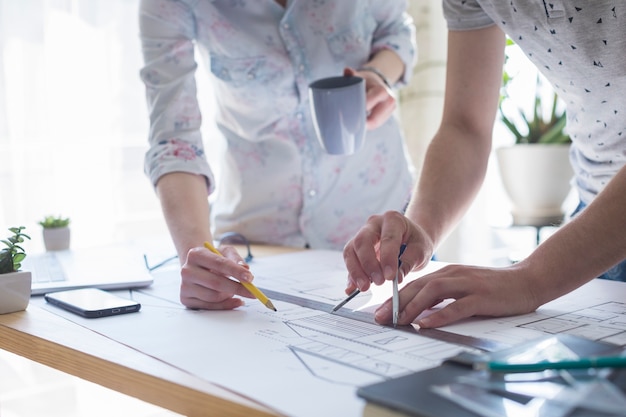 Close-up of architecture hands working on blueprint over wooden table at office