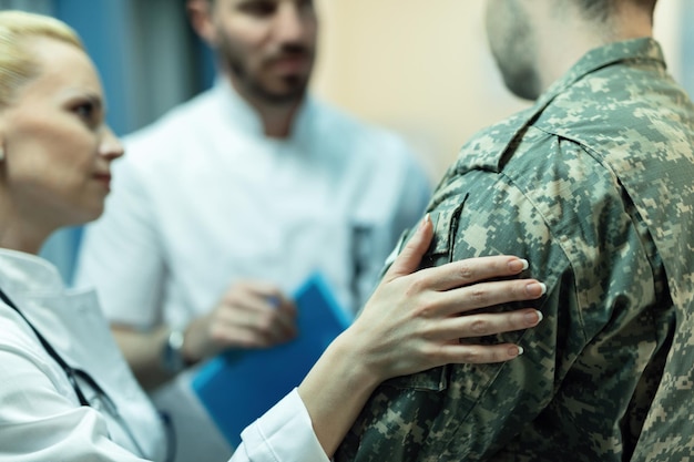 Free photo close up of army soldier being consoled while talking with doctors at clinic