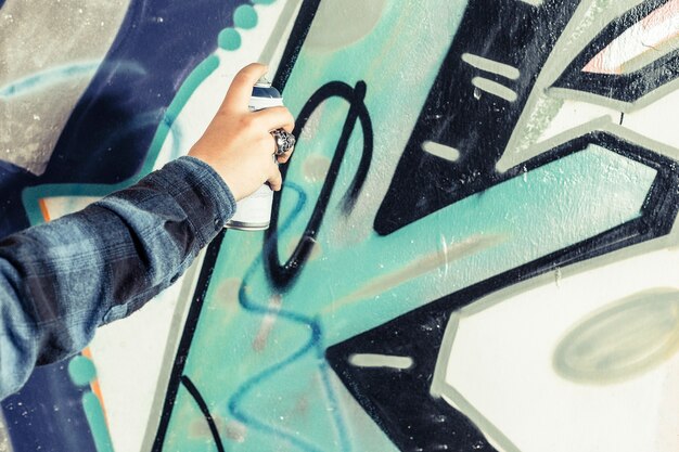 Close-up of an artist's hand painting graffiti on wall