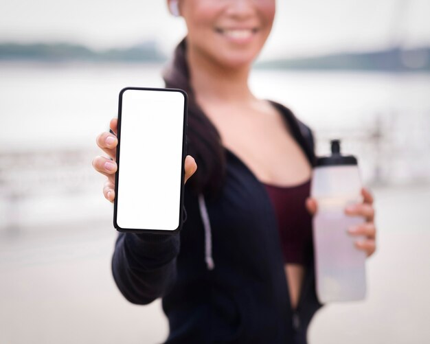 Крупным планом спортивная женщина, держащая мобильный телефон