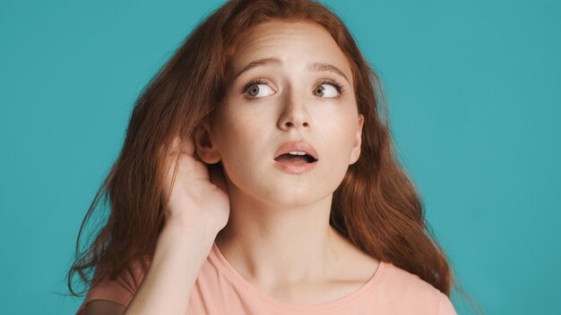 Close up attractive redhead girl trying to hear what saying over colorful background Not hearing expression