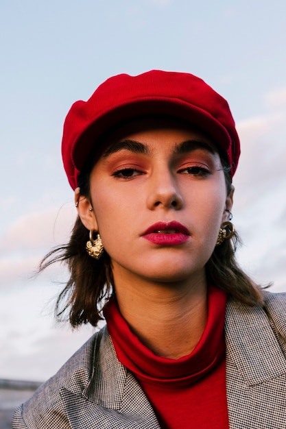 Close-up of an attractive young woman in red cap looking at camera
