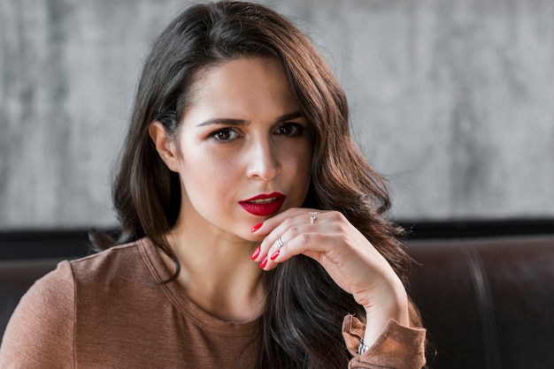 Free photo close-up of an attractive young woman with red lips and nail polish on fingers