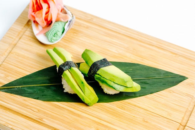 Close up of avocado sashimi served with ginger and wasabi on wood board