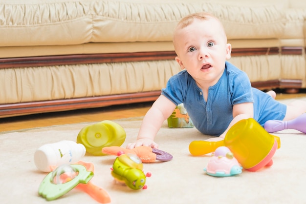 Крупный план ребенок играет с красочными игрушками на ковре