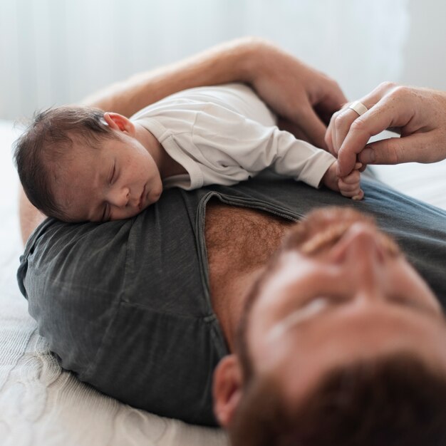お父さんの胸で寝ているクローズアップの赤ちゃん