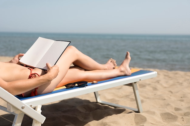 Free photo close up back view woman on beach chair reading