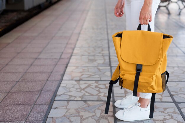 Крупным планом рюкзак и ноги девушки на вокзале
