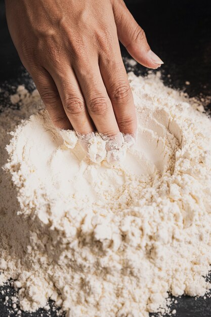 Close-up baker hand preparing flour