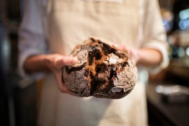 Free photo close up baker holding bread