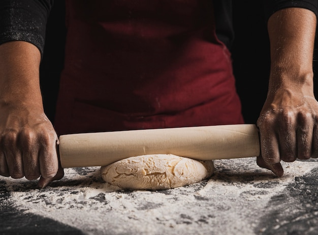 Close-up baker rolling dough composition