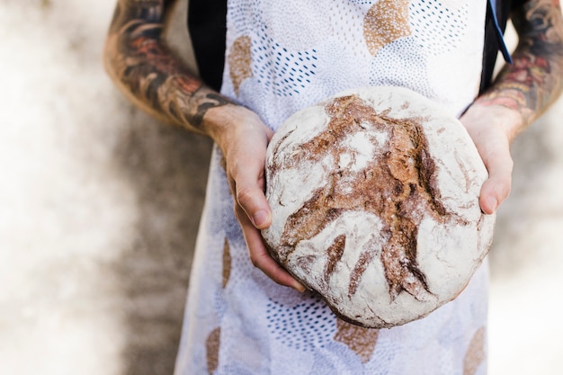 Close-up of a baker's hand holding round rustics bread