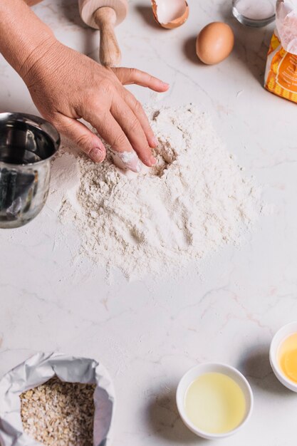 Close-up of a baker's hand with various baking ingredients on kitchen counter