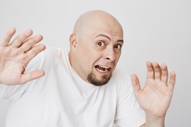 Close-up of bald scared bearded man screaming