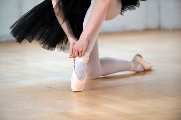 Close up ballerina tying pointe shoes