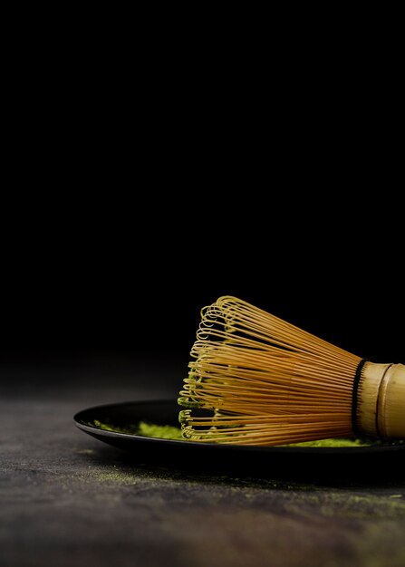 Close-up of bamboo whisk on plate with match tea powder