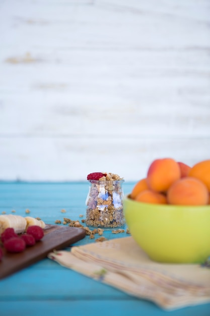 Free photo close-up of banana slices; strawberries; peach and oats on blue wooden surface