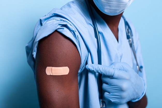 Close up of bandaged vaccine shot on arm of man nurse