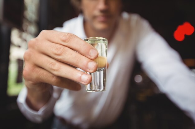 Close-up of bartender holding tequila shot glass at bar counter