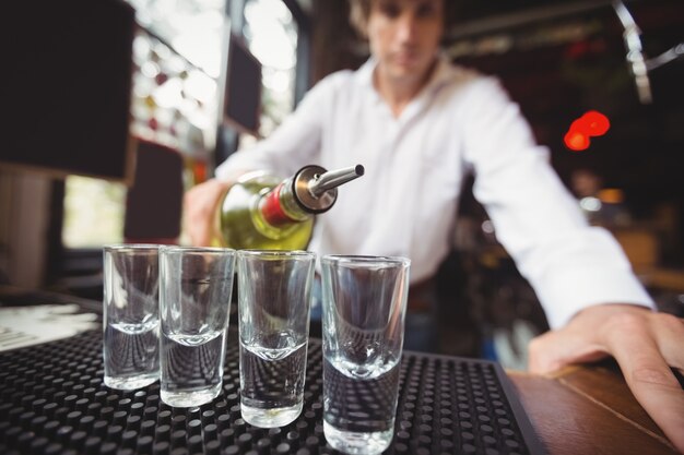 Close-up of bartender pouring tequila in shot glasses