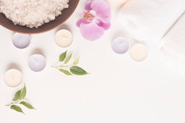 Close-up of bath salt with orchid and candles on white background
