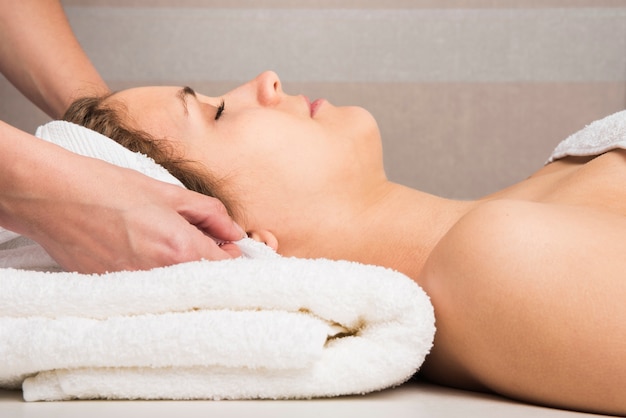 Close-up of a beautician's hand wrapping towel on woman's head